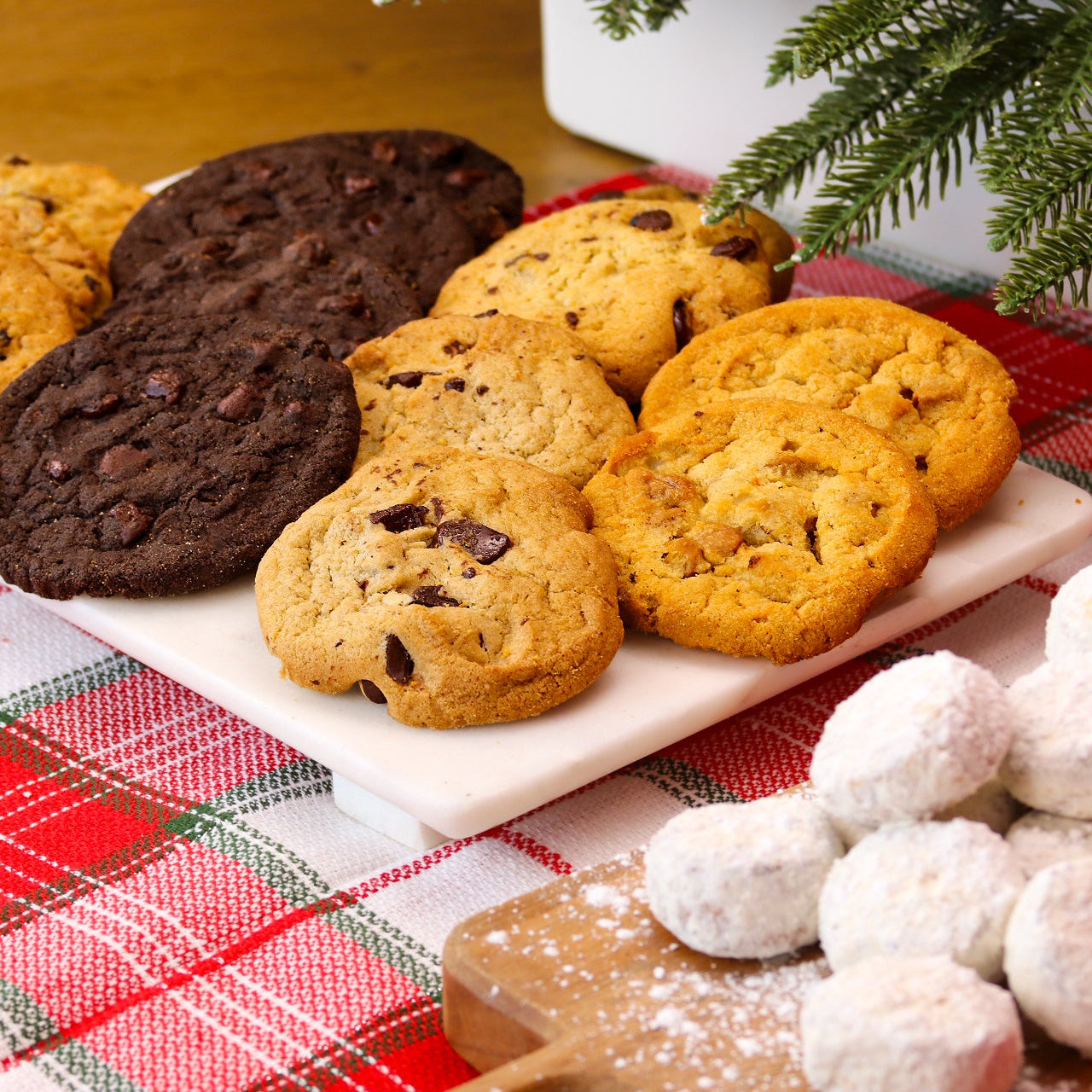 Assorted cookies on a platter with a Christmas tree in the background