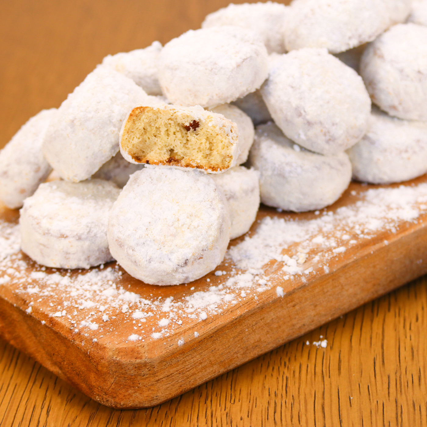 Pile of Butter Pecan Meltaways on a wooden board with one cookie bitten into.