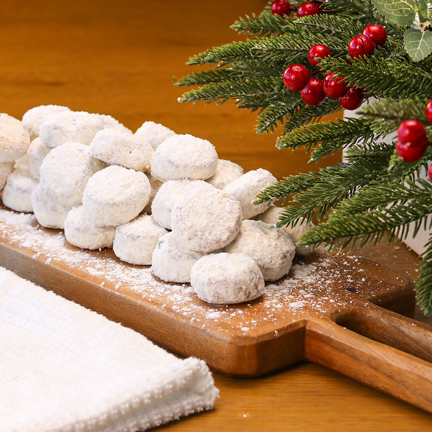 Pile of Butter Pecan Meltaways on a wooden board with a Christmas tree branch in the background.