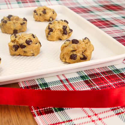 Chocolate chip cookie dough on a white plate with a holiday tablecloth in the background